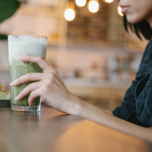 a woman grabs a glass of matcha latte